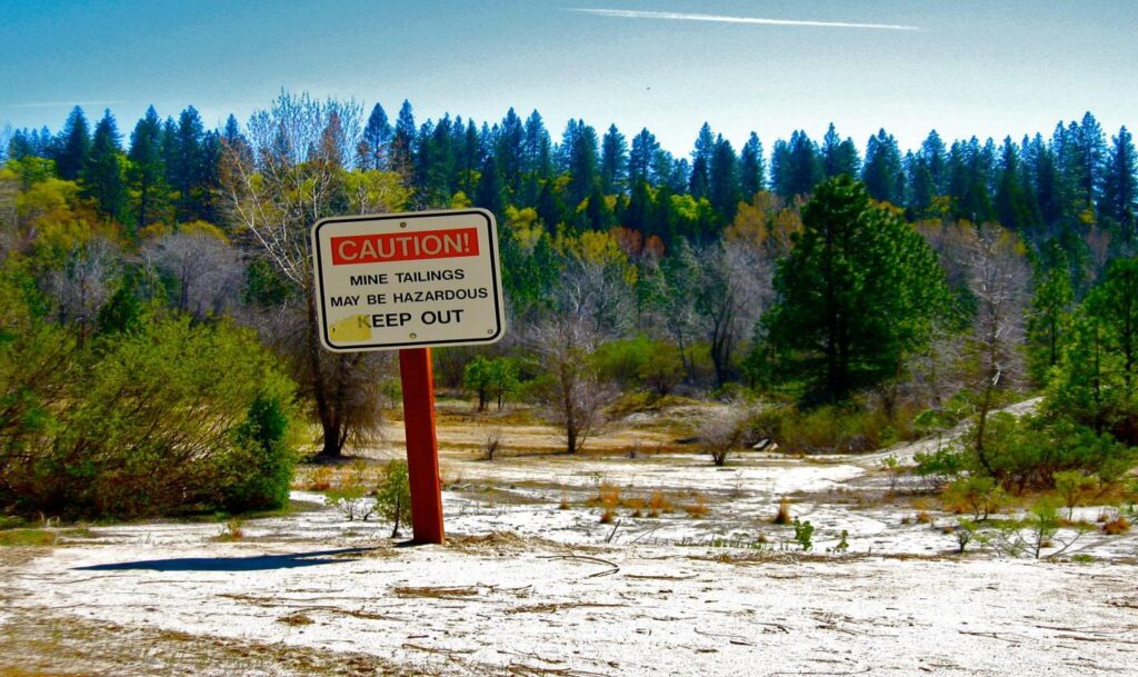 abandoned mine land with sign warning about hazards in mine tailings